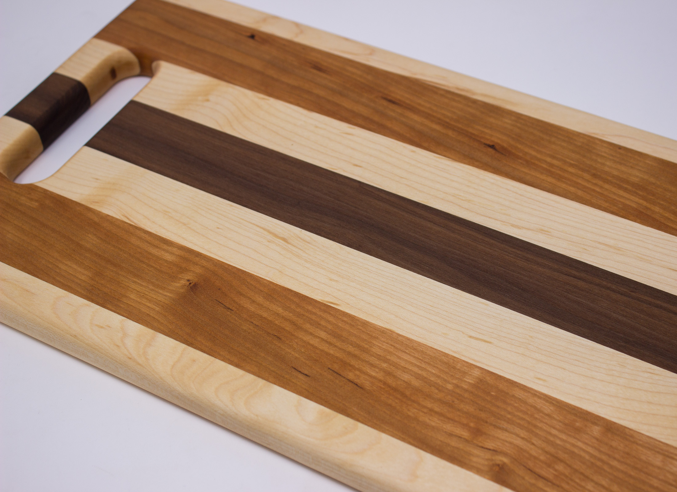 https://www.rockfordwoodcrafts.com/wp-content/uploads/Maple-Cherry-and-Walnut-Cutting-Board-with-Handle-Top-Close-Up.jpg